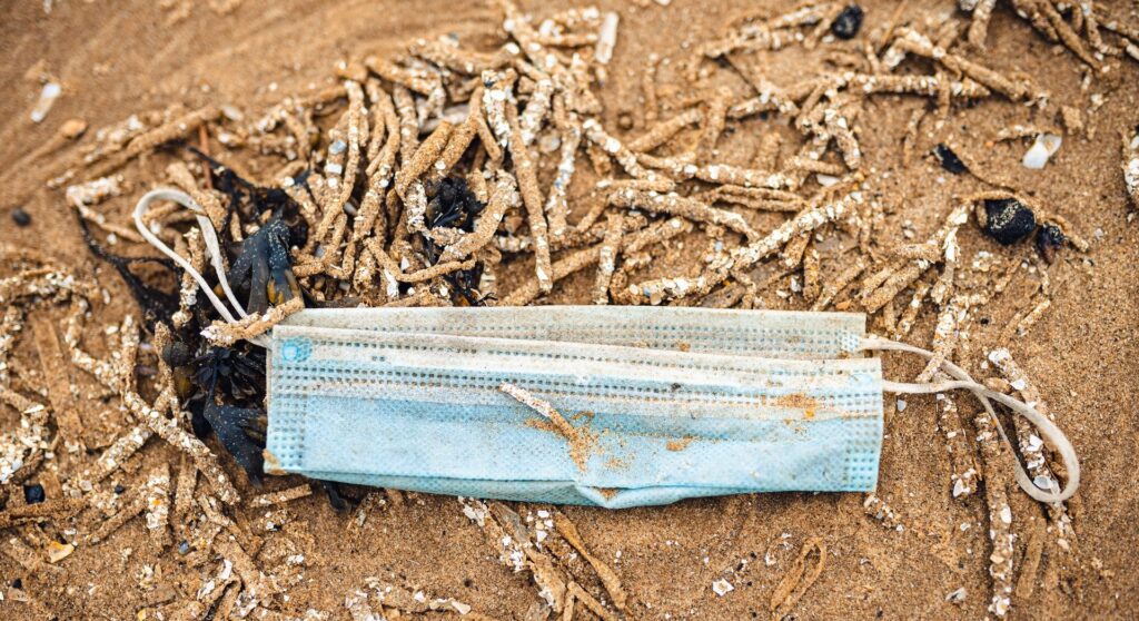 Blue disposable mask washed up on the beach