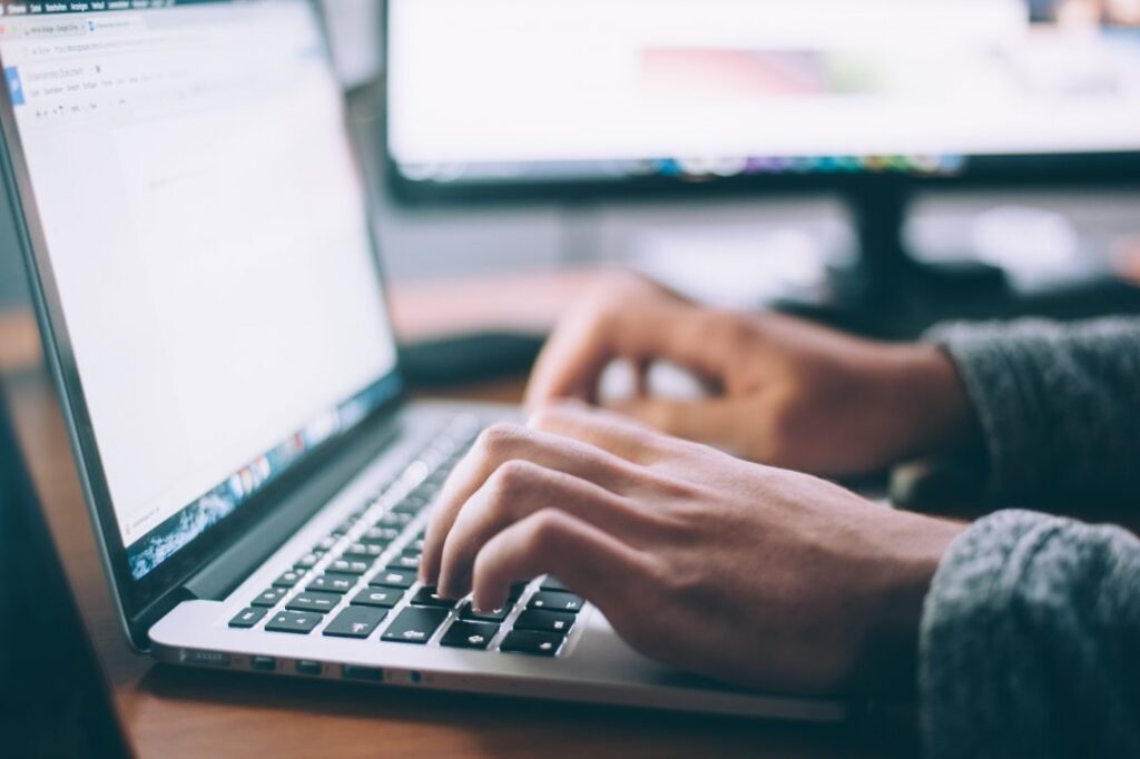 A pair of hands hover over a laptop keyboard