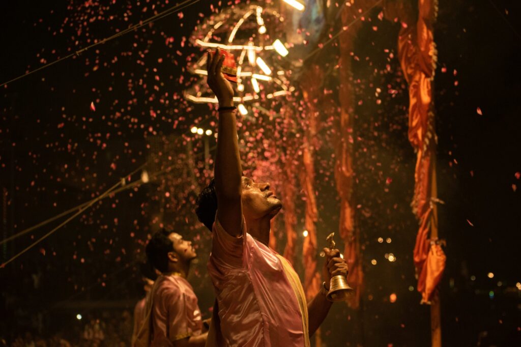 A man reaching up lit from above by twinkling lights