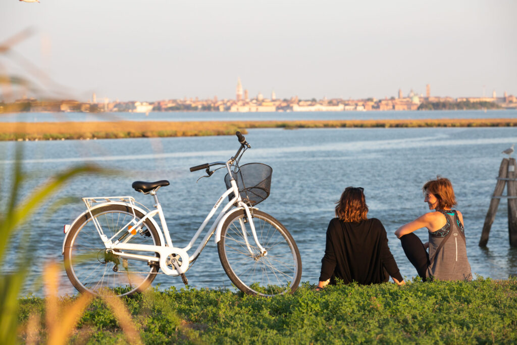 Two women sitting on the banks of a canal in Venice|a man cycling down a quiet road at dusk