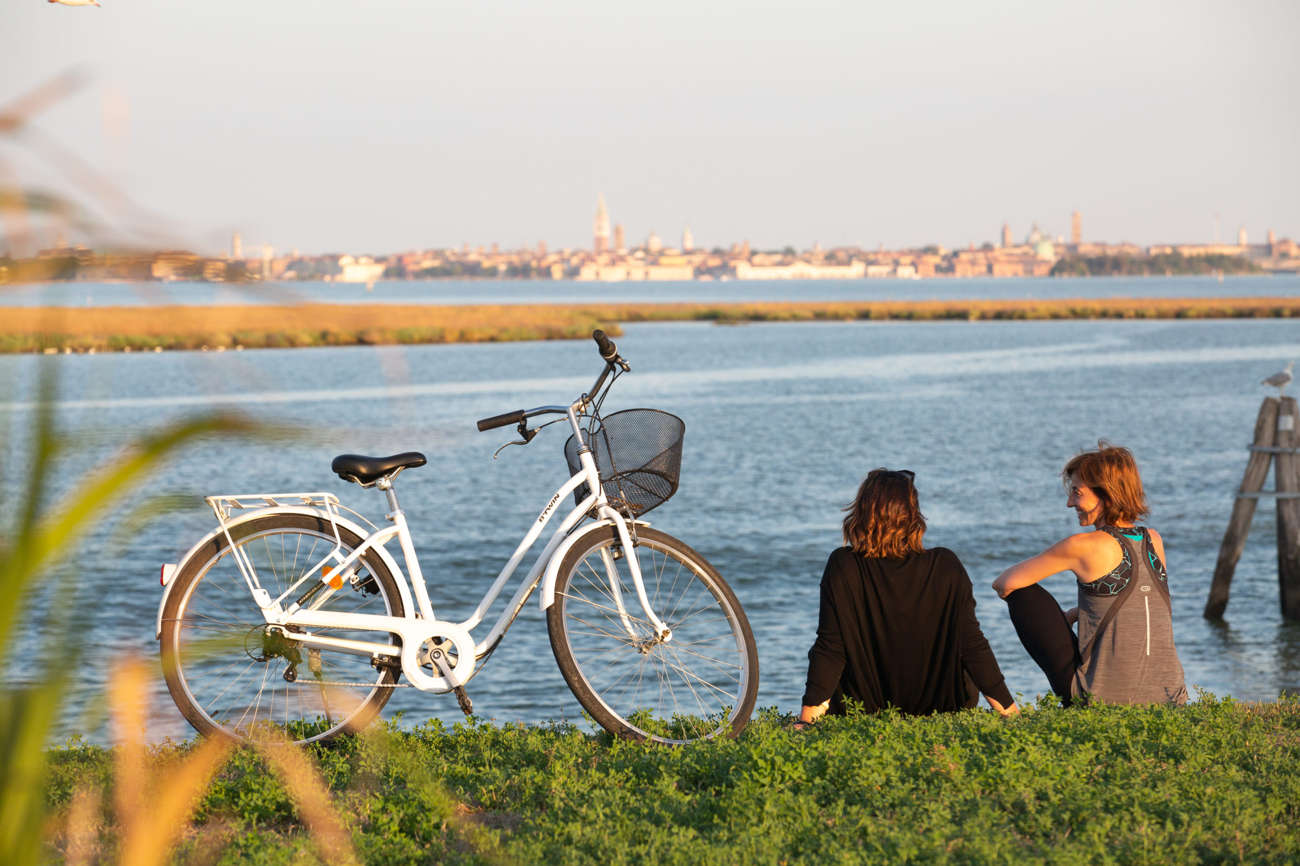 Two women sitting on grass having a conversation facing a stream of water with a bicycle parked along the grass.|A man cycling on the cycle lane in the streets of Venice.|Alexander Schmidt SCC Venice Judge|Jannis Linke SCC Venice Judge|Karen Vancluysen SCC Venice Judge|BetterPoints logo|bikeloop logo|facual logo|HCE logod - no.parking comunica and netmobility|instant system logo|IOKI digital public transport logo.|Kooling Logo|bike party logo|nudgd logo|UrbanTide- love to ride logo|HCE-Logos-Vertical|||
