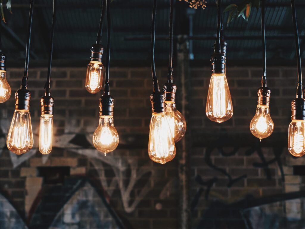 A collection of different types of lightbulbs hang from the ceiling casting a warm glow