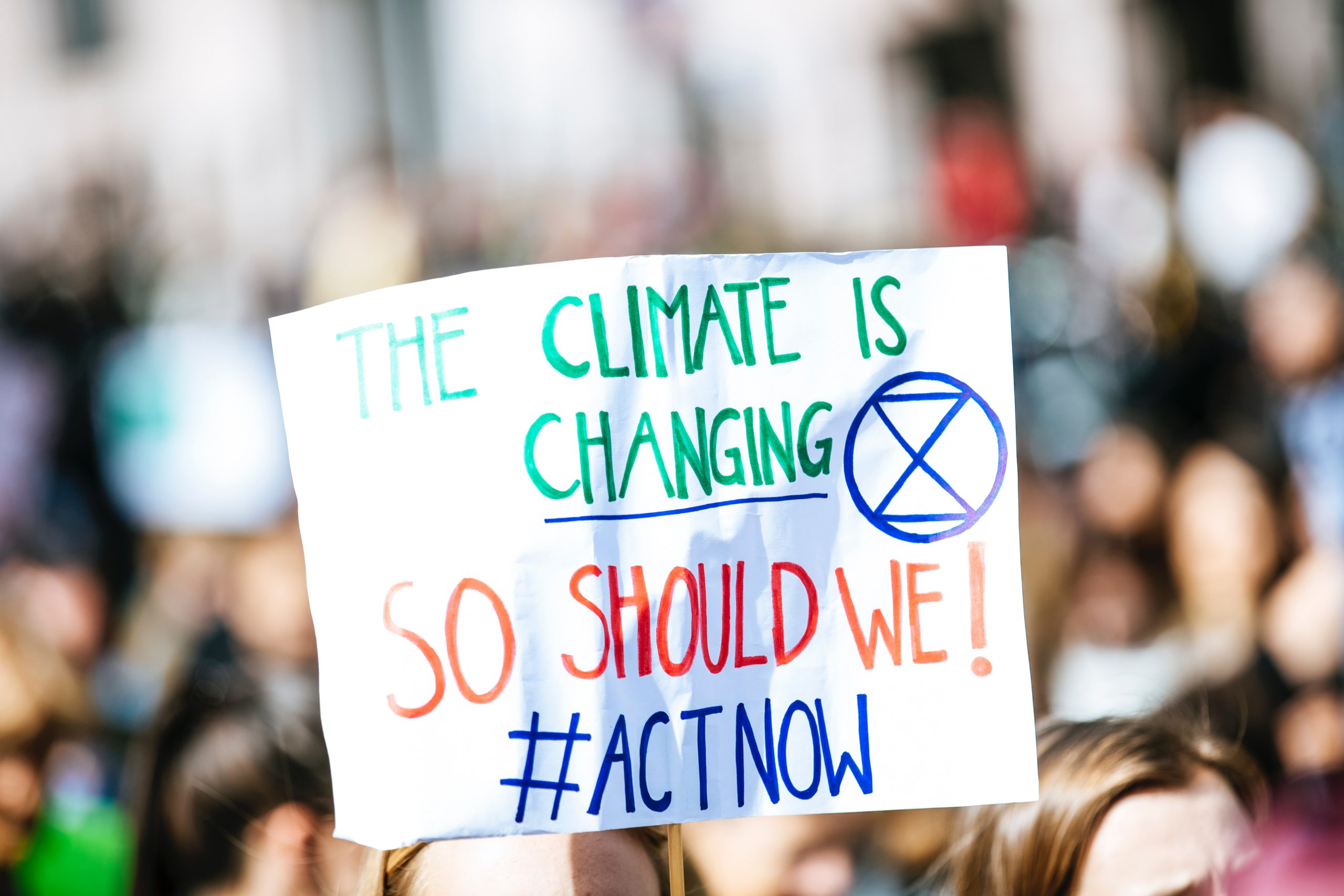 A climate protest sign reads The climate is changing so we should act now!