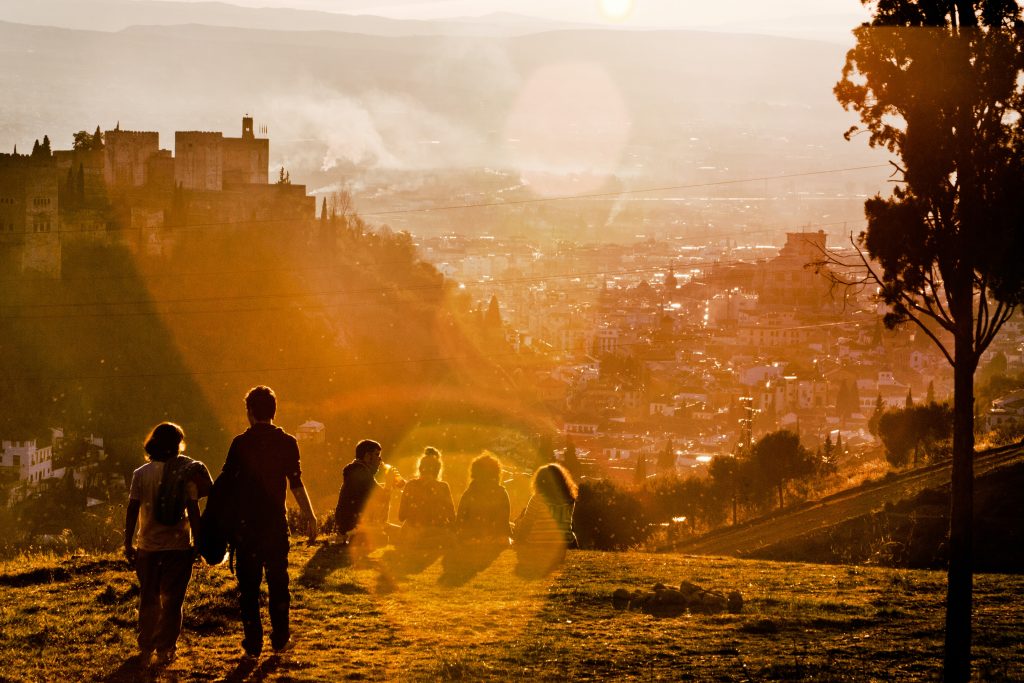 Silhouettes of people against a mountain vista at sunset|